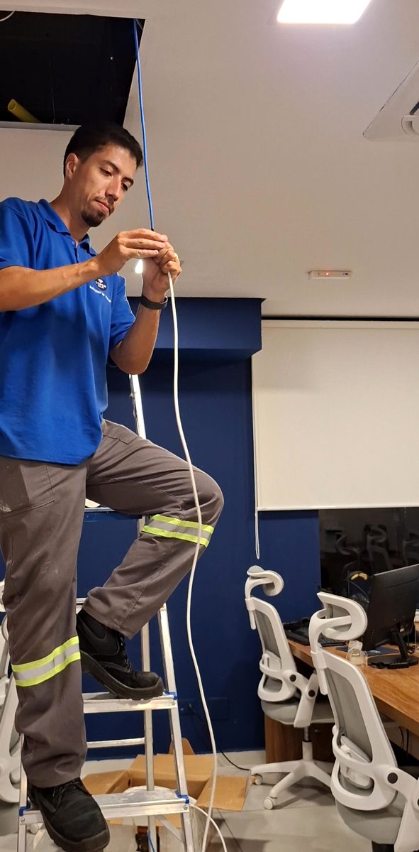 Rafael preparando o cabo de rede de um ponto no alto de uma escada